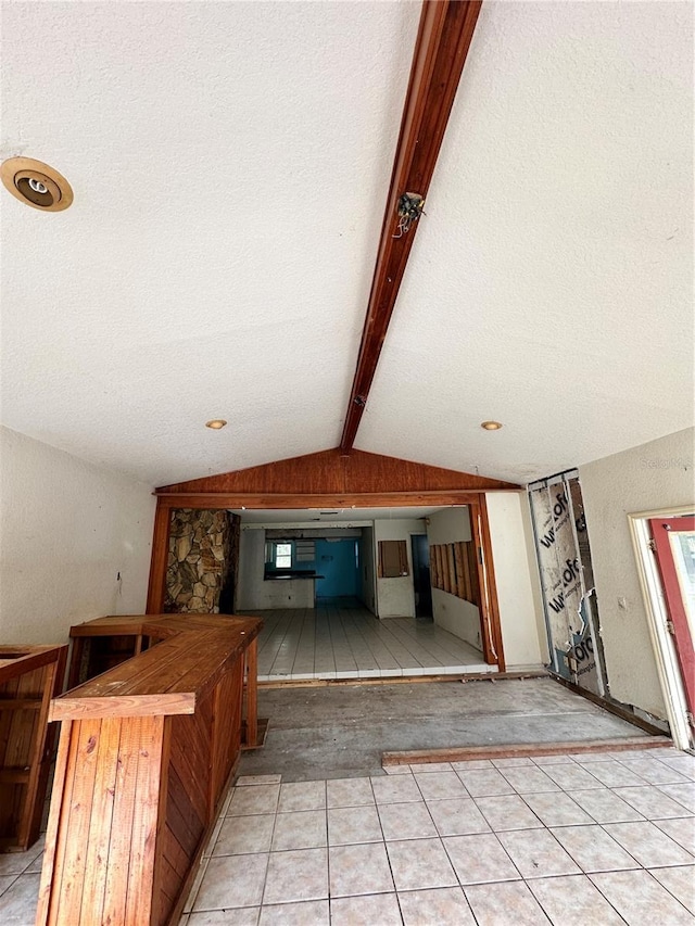 kitchen featuring a textured ceiling, lofted ceiling with beams, and light tile patterned floors