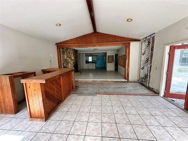 interior space featuring vaulted ceiling with beams, light tile patterned flooring, and a textured ceiling