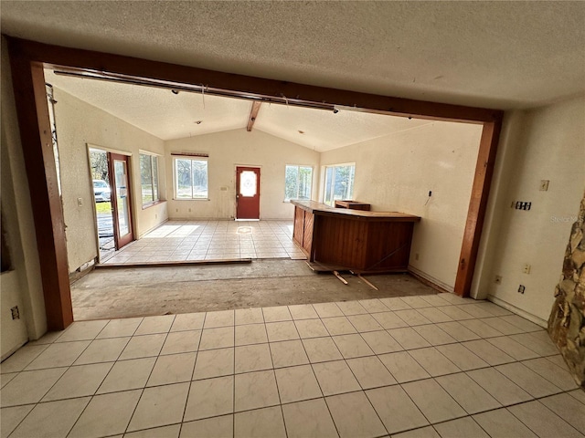 kitchen featuring a textured ceiling, lofted ceiling with beams, and light tile patterned floors