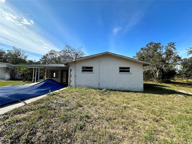 rear view of house with a lawn and a carport