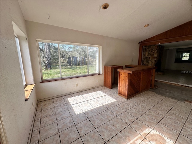 17025 Dalberg Dr, Spring Hill, FL 34610 - bar area featuring lofted ceiling, light tile patterned floors, and a textured wall