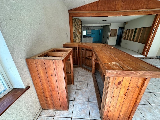 17025 Dalberg Dr, Spring Hill, FL 34610 - bar area with lofted ceiling, a textured wall, and light tile patterned flooring