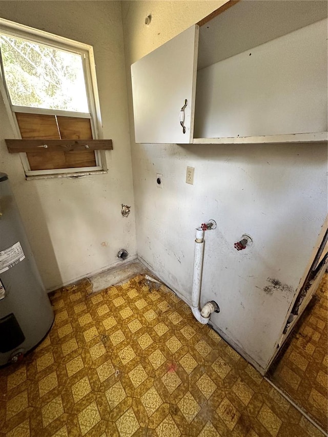 clothes washing area with water heater, electric dryer hookup, and cabinets