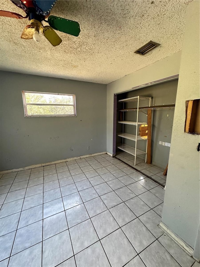 tiled empty room featuring a textured ceiling and ceiling fan