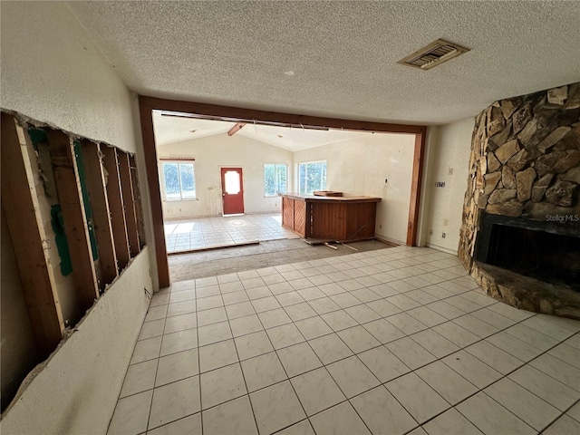 unfurnished living room featuring lofted ceiling with beams, a textured ceiling, a fireplace, and light tile patterned floors