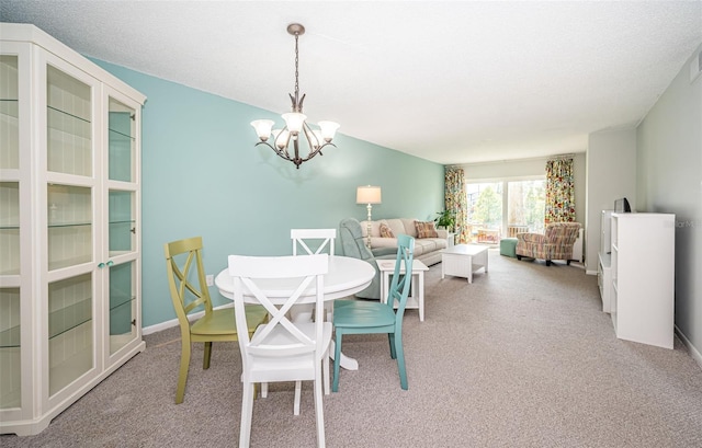 dining room featuring a chandelier, a textured ceiling, and carpet flooring