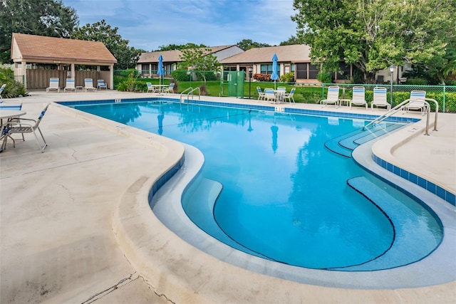 view of pool with a patio and a lawn