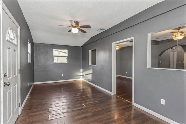 unfurnished room featuring a textured ceiling, lofted ceiling, and dark hardwood / wood-style flooring