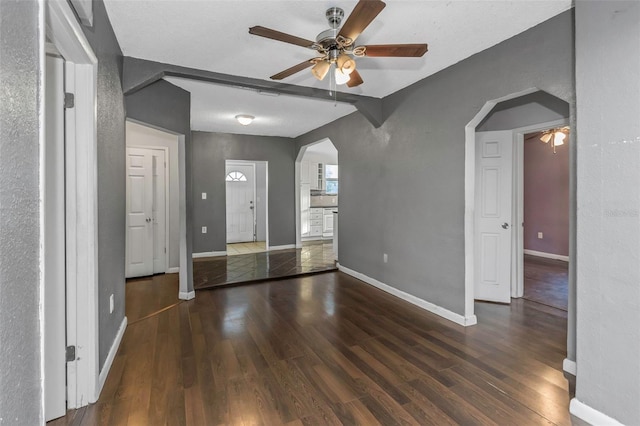 interior space with dark hardwood / wood-style flooring, beamed ceiling, and ceiling fan