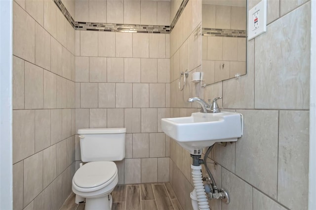 bathroom featuring hardwood / wood-style flooring, tile walls, and toilet