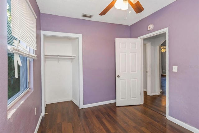 unfurnished bedroom featuring ceiling fan, a closet, dark wood-type flooring, and multiple windows