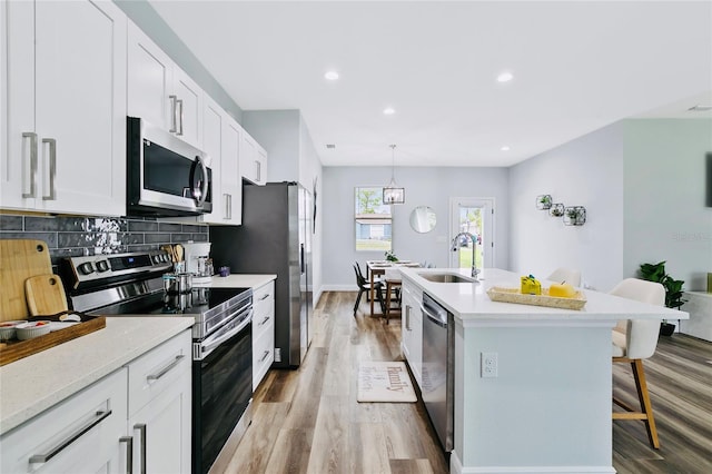 16451 Strauss Ave, Port Charlotte, FL 33954 - kitchen with stainless steel appliances, a sink, a kitchen breakfast bar, backsplash, and a kitchen island with sink