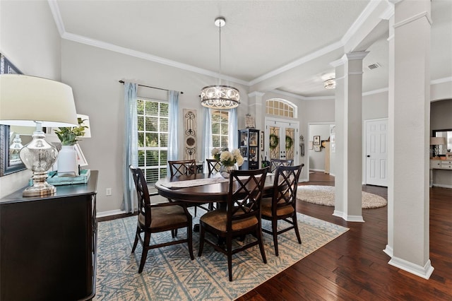 dining space featuring ornate columns, ornamental molding, a chandelier, and dark wood-type flooring