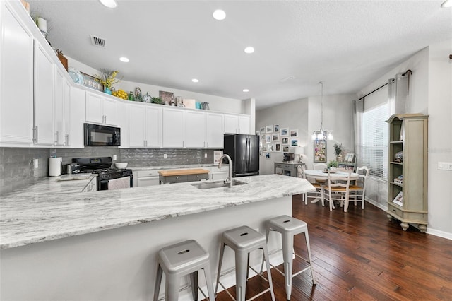 kitchen featuring white cabinetry, kitchen peninsula, dark hardwood / wood-style flooring, black appliances, and sink