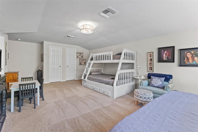 carpeted bedroom featuring a textured ceiling and lofted ceiling