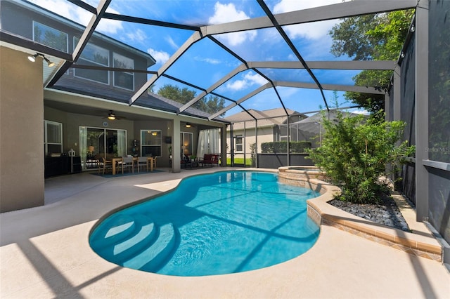 view of swimming pool featuring ceiling fan, glass enclosure, a patio area, and an in ground hot tub