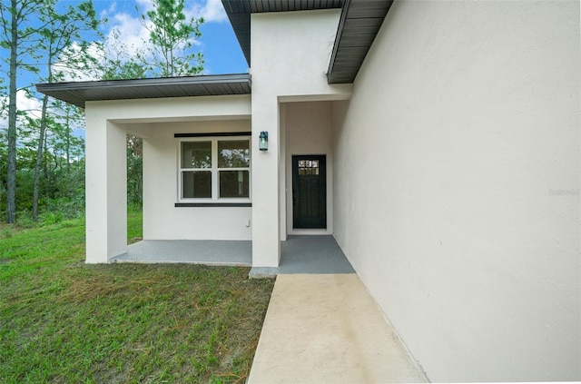 view of exterior entry featuring covered porch and a yard