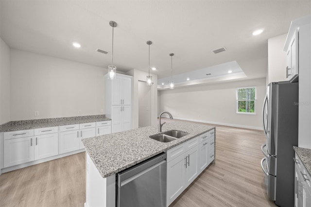 kitchen featuring pendant lighting, sink, a center island with sink, white cabinetry, and appliances with stainless steel finishes