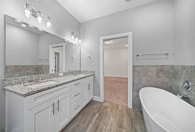 bathroom with tile walls, a tub to relax in, hardwood / wood-style flooring, and vanity