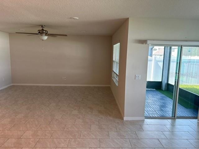 tiled empty room featuring ceiling fan and a textured ceiling