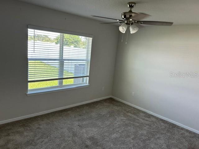 carpeted spare room featuring a ceiling fan and baseboards