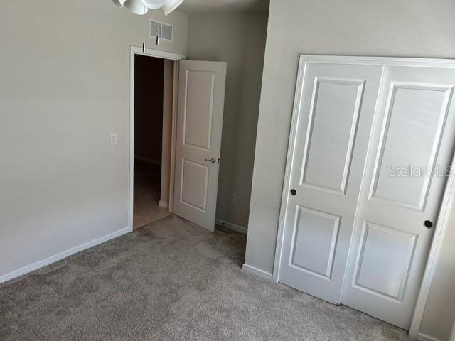 unfurnished bedroom featuring light colored carpet and a closet