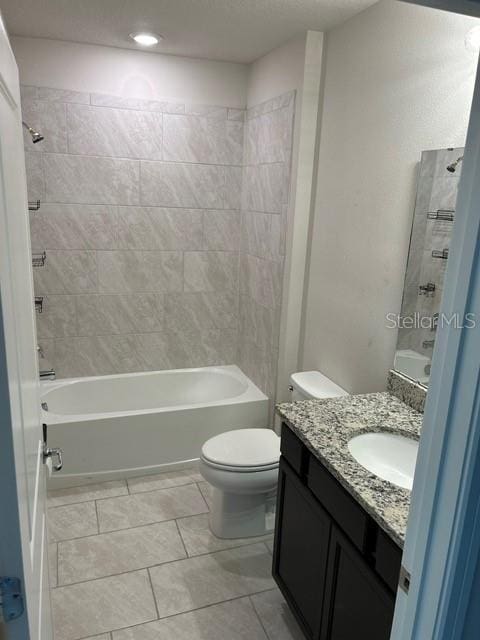 full bathroom with tiled shower / bath, vanity, tile patterned flooring, and toilet