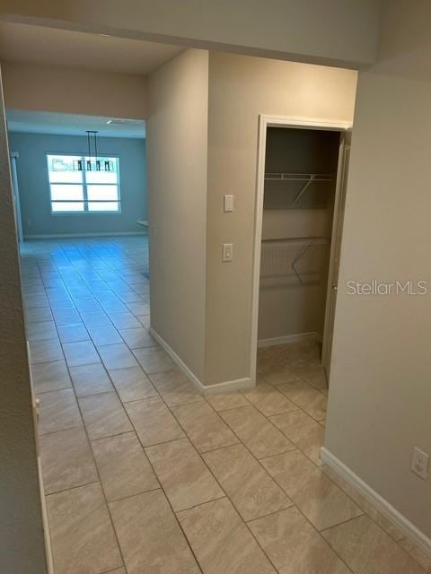 corridor with light tile patterned floors and baseboards