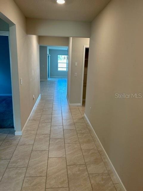hall with light tile patterned floors and baseboards
