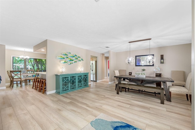 dining space featuring light hardwood / wood-style flooring and an inviting chandelier