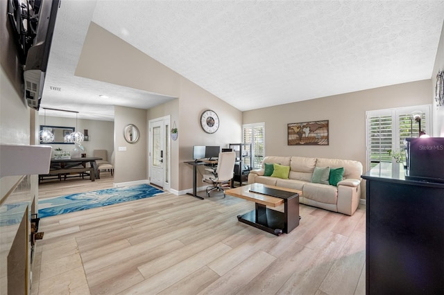 living room with light wood-type flooring, a textured ceiling, lofted ceiling, and plenty of natural light