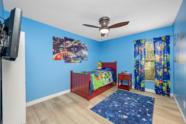 bedroom with ceiling fan, hardwood / wood-style flooring, and a textured ceiling