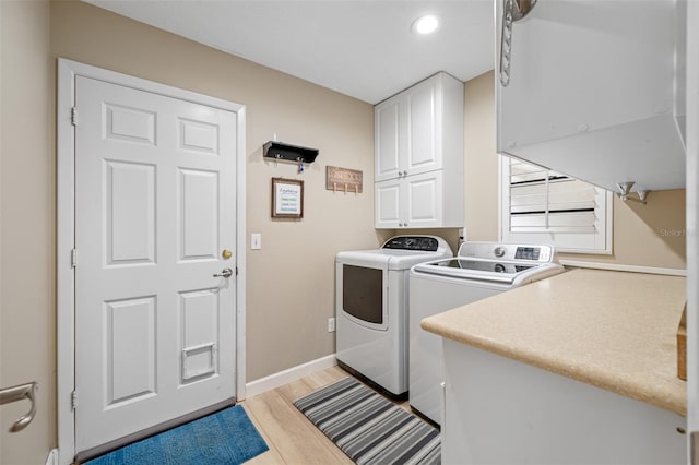 clothes washing area with cabinets, light wood-type flooring, and washer and dryer