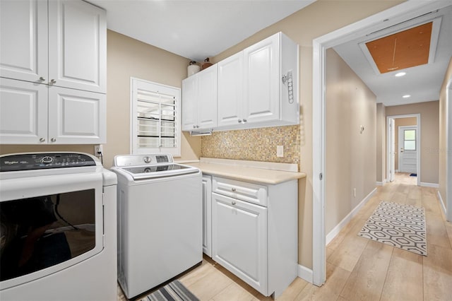 clothes washing area featuring separate washer and dryer, cabinets, and light hardwood / wood-style floors