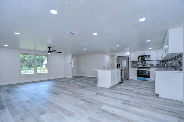 kitchen featuring a kitchen island with sink, stainless steel appliances, light wood-type flooring, white cabinetry, and ceiling fan