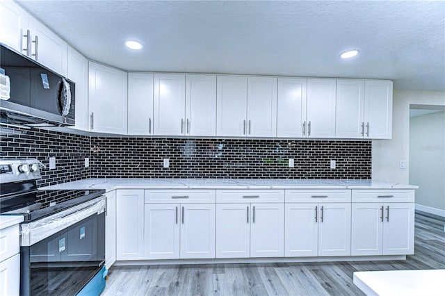 kitchen featuring white cabinets, tasteful backsplash, light stone counters, light hardwood / wood-style flooring, and stainless steel appliances