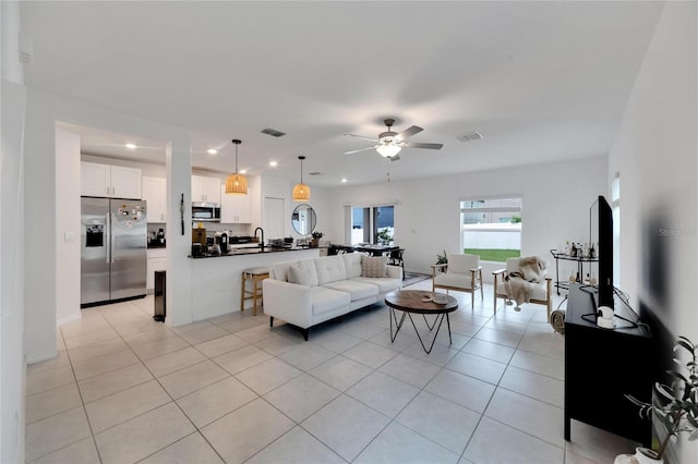 living room featuring light tile patterned flooring, sink, and ceiling fan