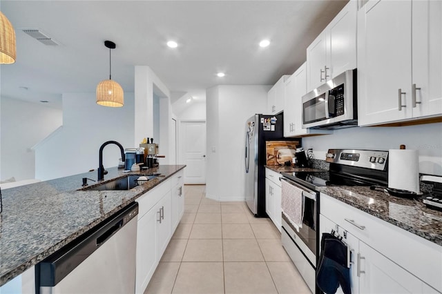 kitchen with sink, white cabinetry, stainless steel appliances, dark stone counters, and decorative light fixtures