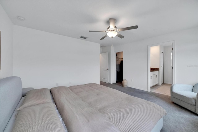 bedroom featuring ensuite bathroom, a spacious closet, a closet, light carpet, and ceiling fan