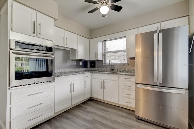 kitchen with ceiling fan, white cabinets, sink, light hardwood / wood-style floors, and appliances with stainless steel finishes