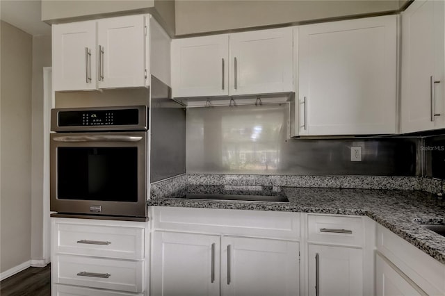 kitchen featuring dark hardwood / wood-style floors, white cabinets, dark stone countertops, stainless steel oven, and black electric stovetop