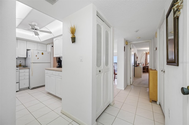 kitchen featuring a textured ceiling, white cabinetry, white appliances, light tile patterned floors, and ceiling fan