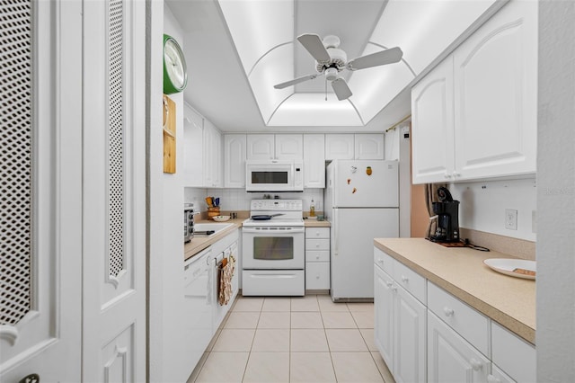 kitchen with white appliances, a raised ceiling, white cabinetry, and light tile patterned floors