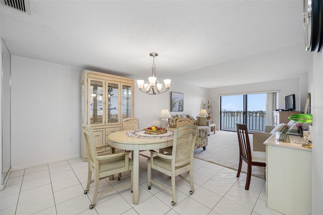 dining area featuring a notable chandelier, a textured ceiling, and light tile patterned floors