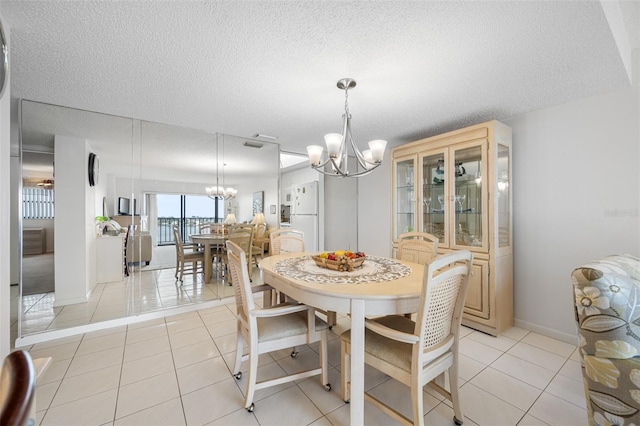 dining space featuring a textured ceiling, light tile patterned floors, and a chandelier