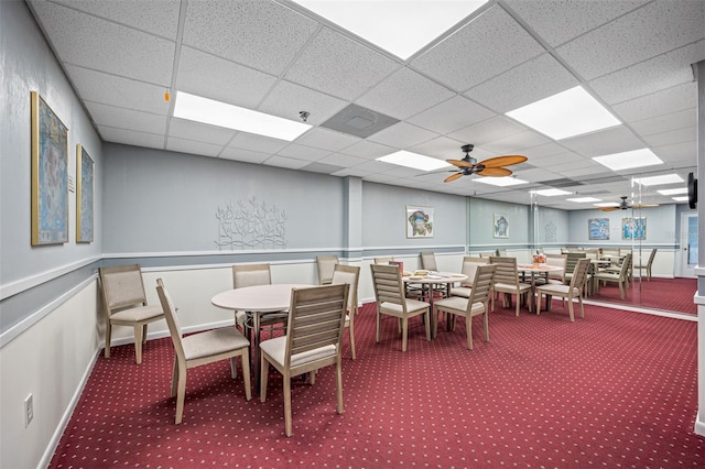 carpeted dining room with ceiling fan and a paneled ceiling