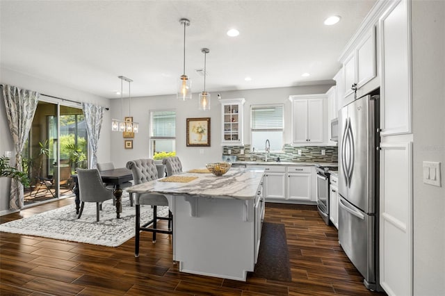 kitchen with stainless steel appliances, pendant lighting, white cabinets, a breakfast bar area, and a center island