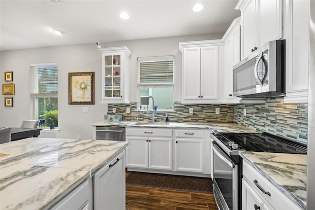 kitchen featuring tasteful backsplash, appliances with stainless steel finishes, dark hardwood / wood-style floors, light stone countertops, and white cabinets