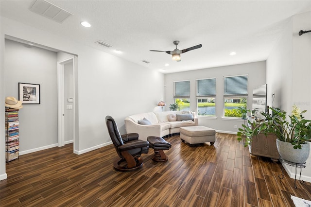 living room featuring ceiling fan, a textured ceiling, and dark hardwood / wood-style floors