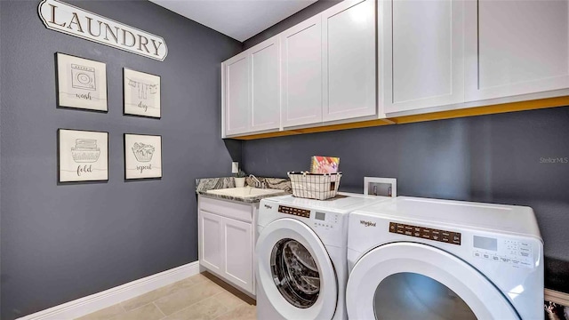 laundry room featuring cabinets, light tile patterned floors, and washer and dryer